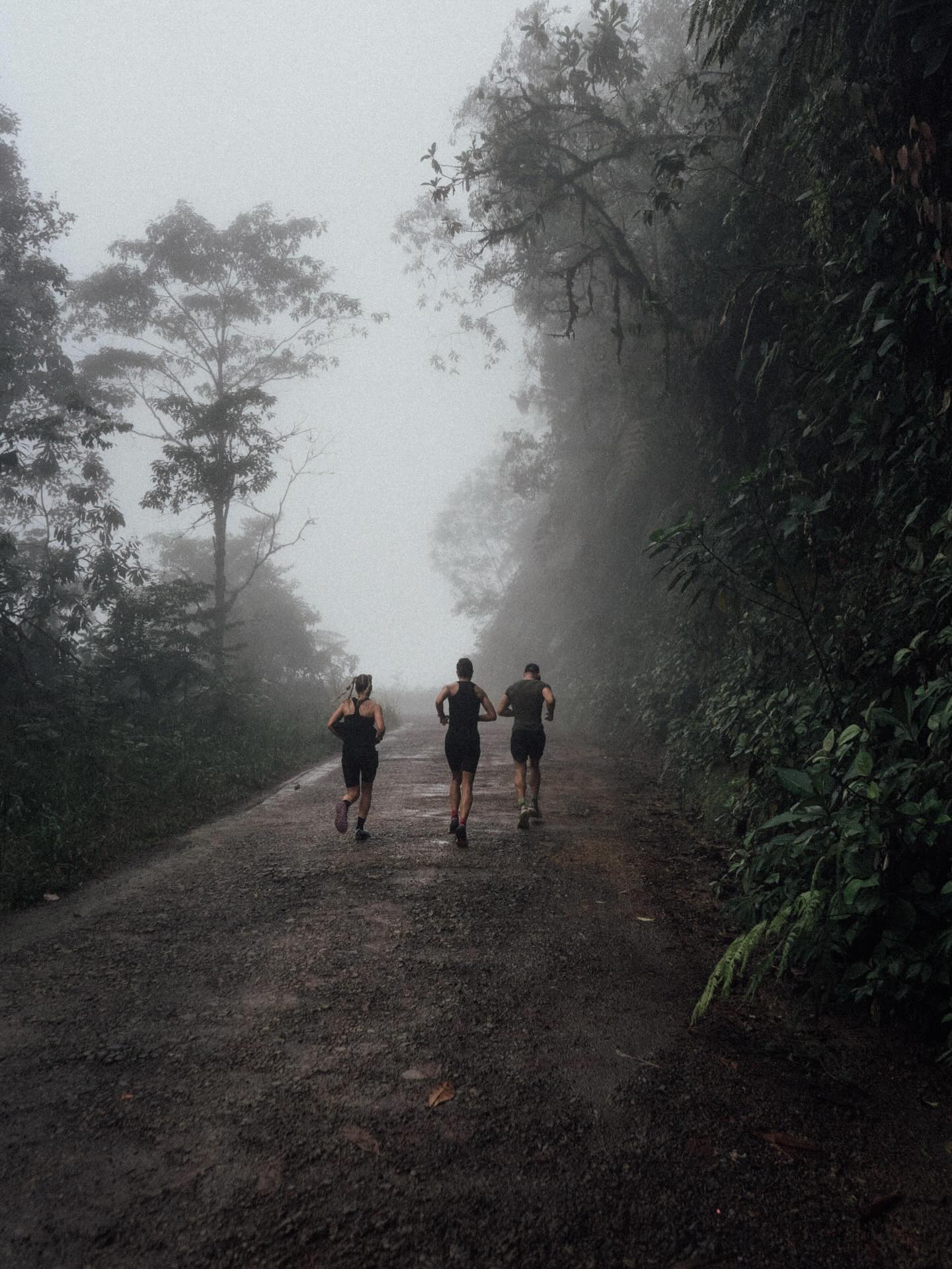 Paweł running with two others through fog-covered jungle trail