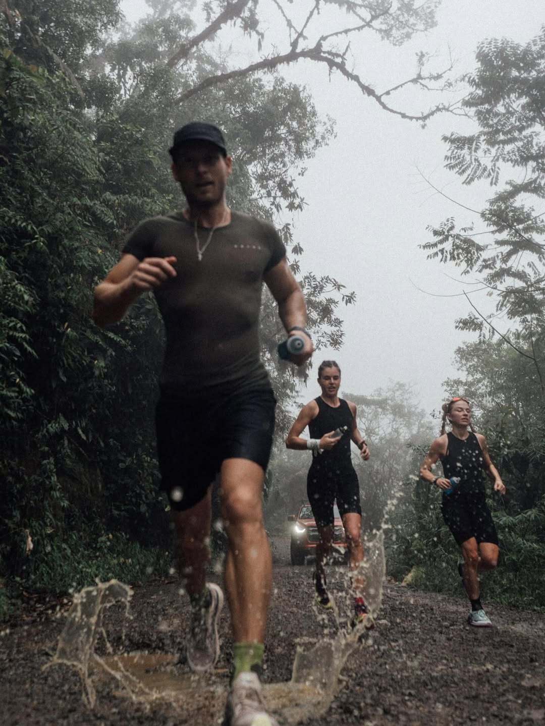 Paweł running with two athletes in fog-covered jungle